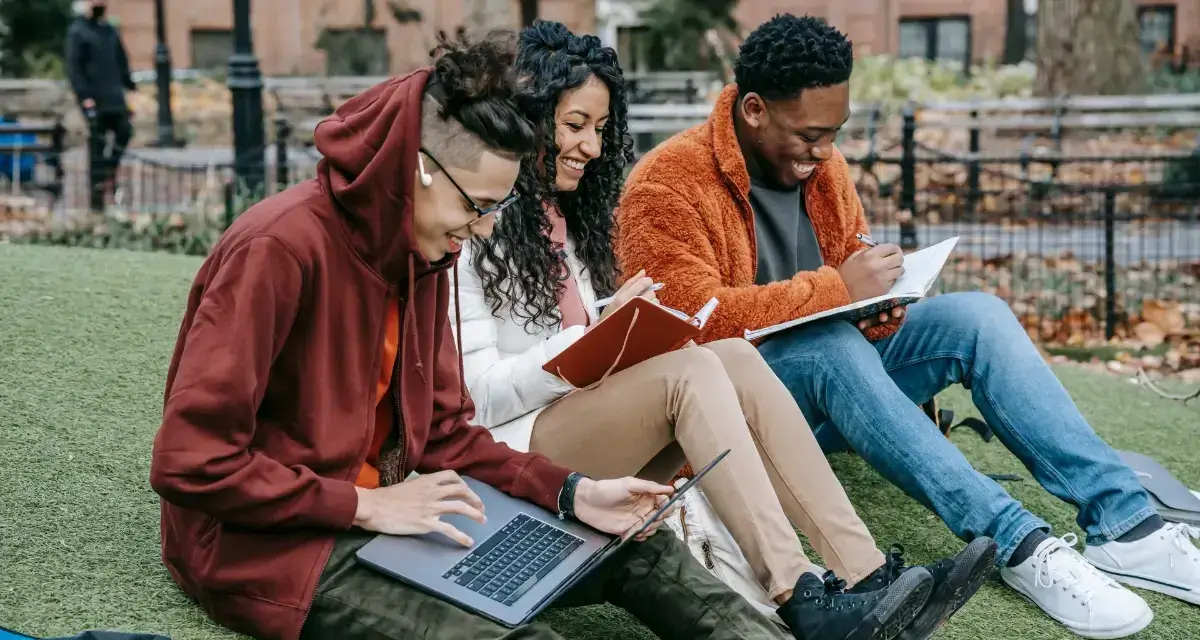 Cheerful diverse classmates studying in the park